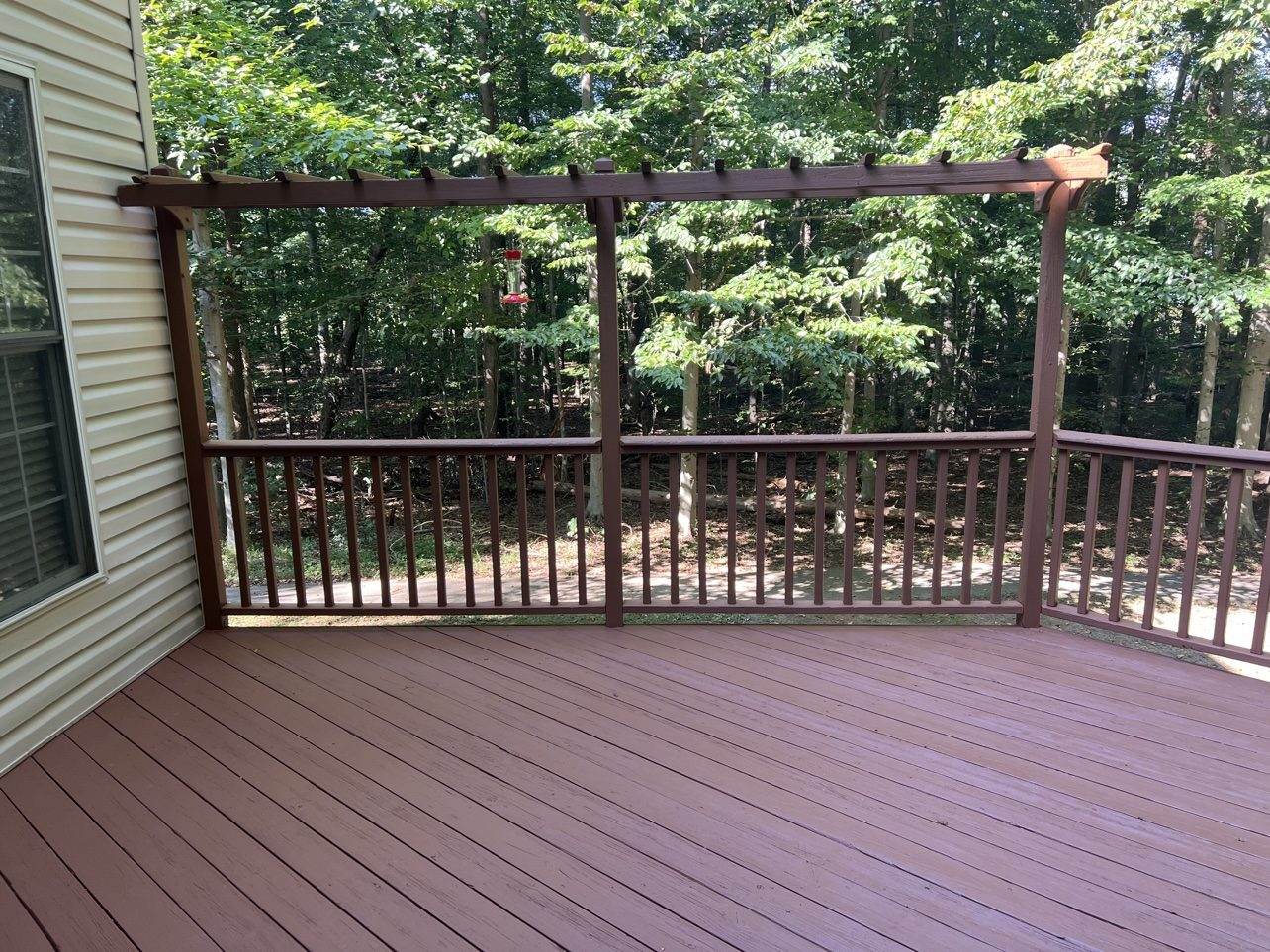 The same pergola deck after fresh red stain — the payoff side of the cost equation.