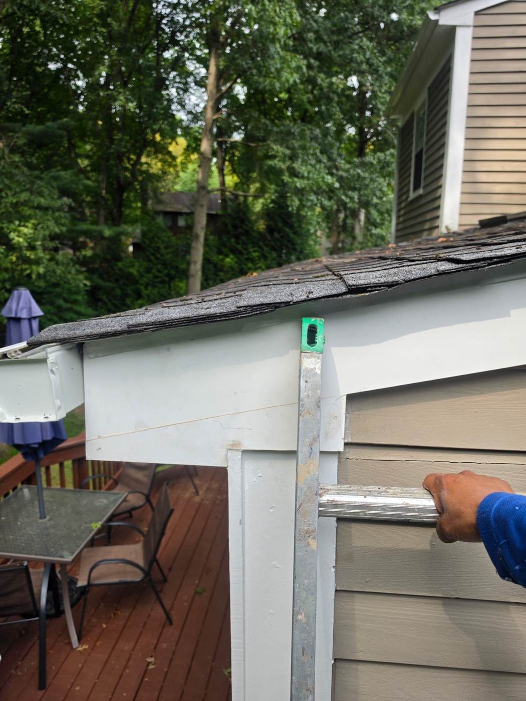 Working a gutter end cap and fascia repair at the roof edge — sectional joints need resealing and attention over time.